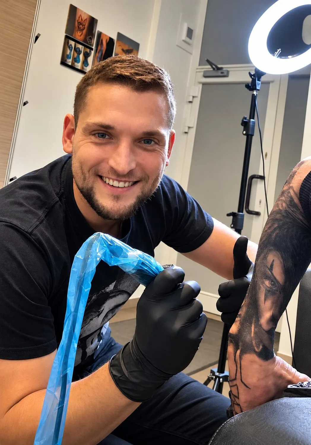 Tatuażysta ze studia To Jest To Tattoo w Częstochowie podczas pracy, w czarnych rękawiczkach przygotowuje maszynkę nad przedramieniem klienta